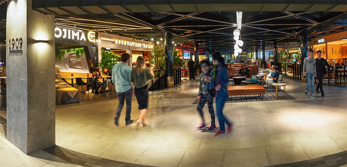 People walking through the 1909 Dining Precinct, past restaurants and a lounge seating area